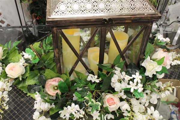 a glass cage with candles in it with floral vines