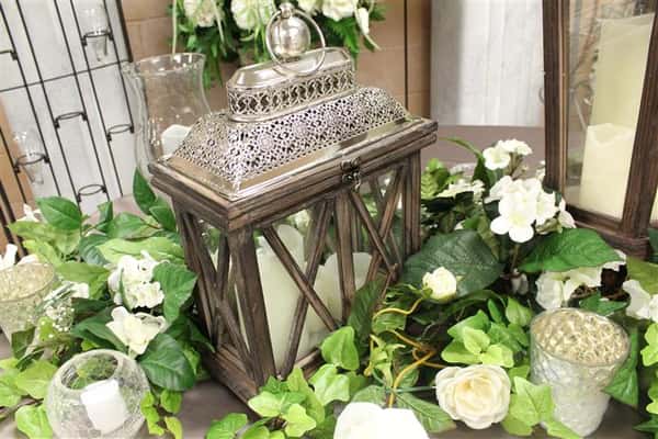 a glass cage with candles in it with floral vines