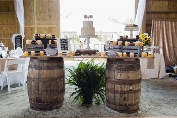 wooden barrels holding up a dessert table with a wedding cake