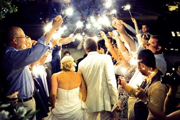 Guests holding sparklers over the bride and groom