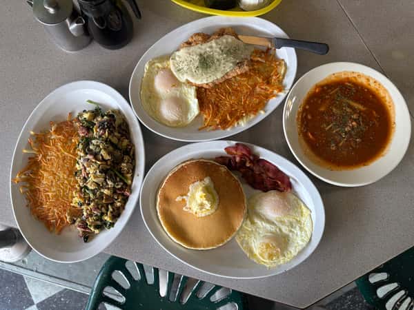 A Tennessee Grill table displays four plates of various breakfast meals.