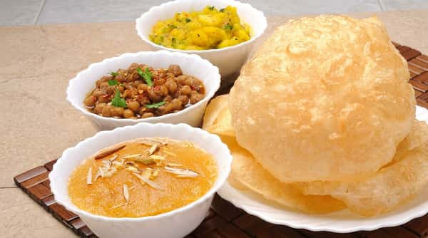 Fluffy puri served with chana masala, sweet halwa, and aloo sabzi at Chaat Diner, a pure vegetarian Indian restaurant in San Francisco.