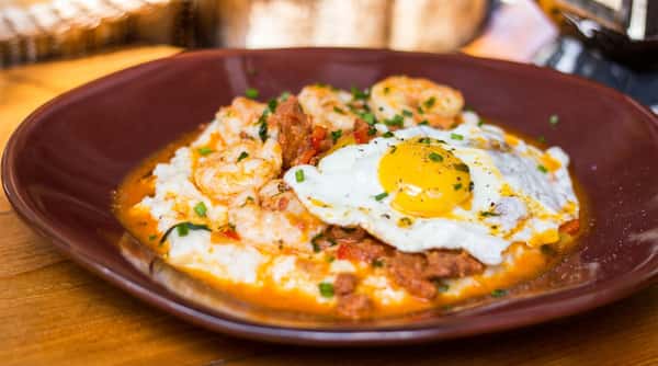 Creamy stone-ground grits topped with sautéed shrimp, house-made sausage, and a sunny-side-up egg in a rich, flavorful sauce.