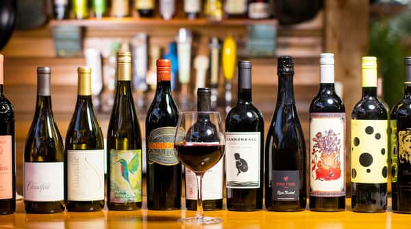 A curated selection of wines displayed behind the bar, featuring reds, whites, and sparkling varietals available by the glass or bottle.