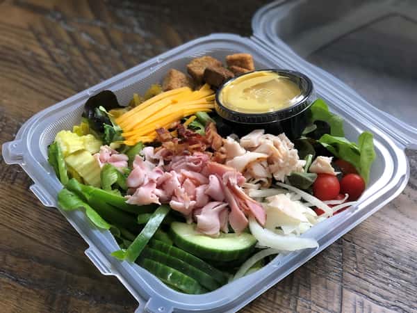 italian godfather salad with a side of dressing in a plastic container