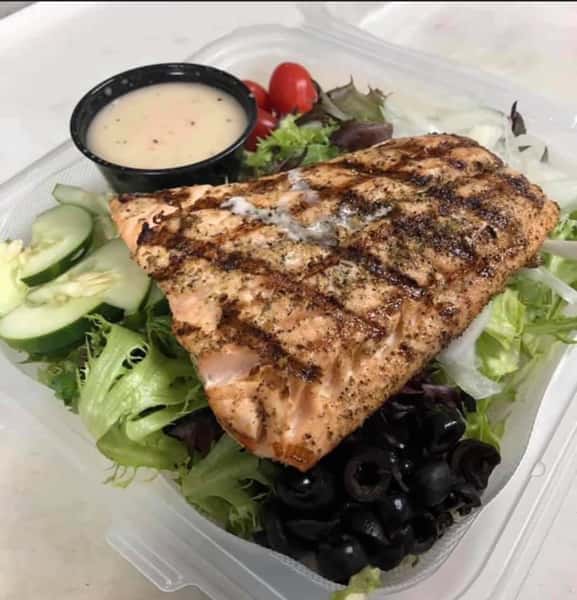 garden salad topped with grilled salmon and dressing