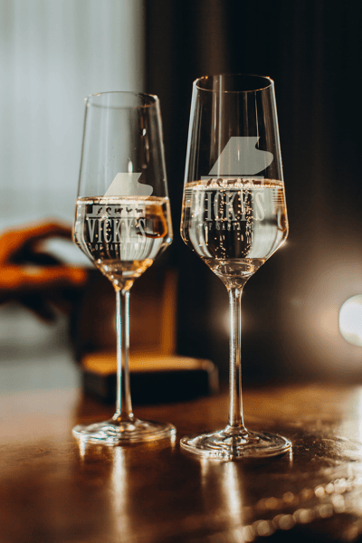 2 full glasses of champagne in etched flutes with the Vicky's logo