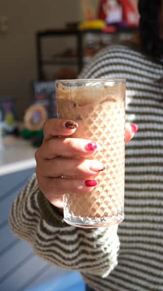 Person holding up a glass of iced coffee
