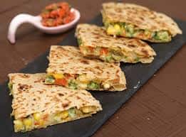 Vegetable-stuffed quesadillas cut into triangles on a black slate plate