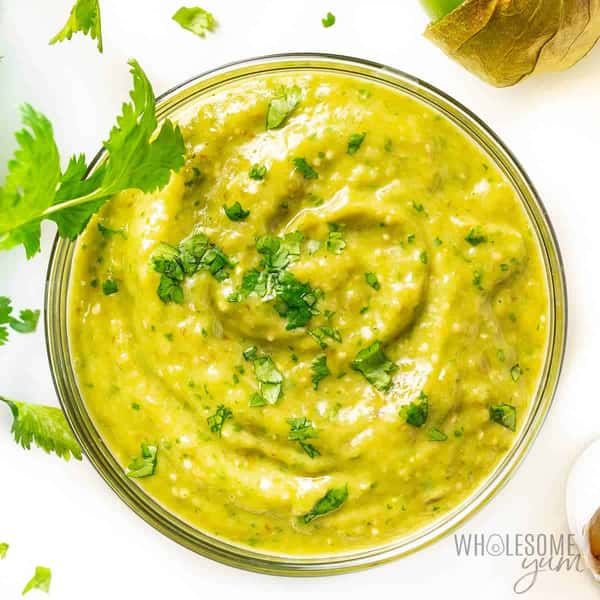 Creamy green tomatillo salsa garnished with fresh cilantro in a glass bowl.