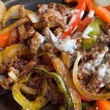 Beef fajitas with grilled bell peppers and onions on a hot skillet