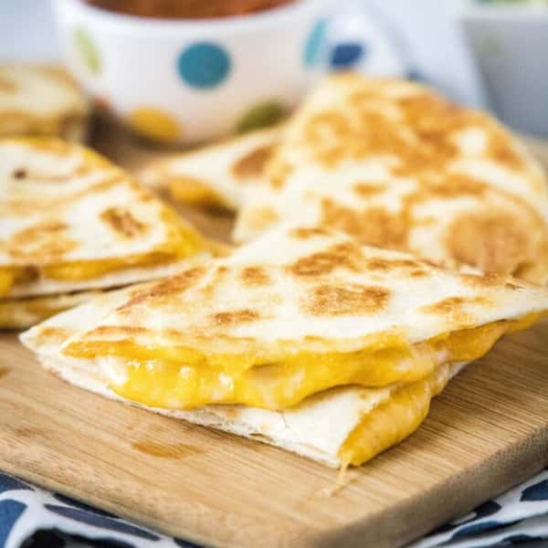 Cheddar cheese quesadillas cut into triangles on a wooden board.