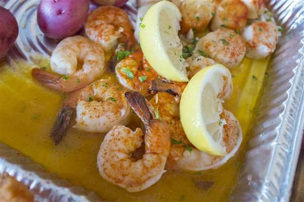shrimp in an oil sauce with lemon wedges