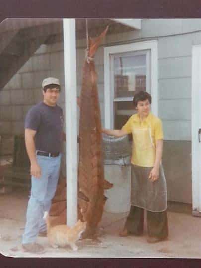 an old photo of two people posing next to a big fish they caught