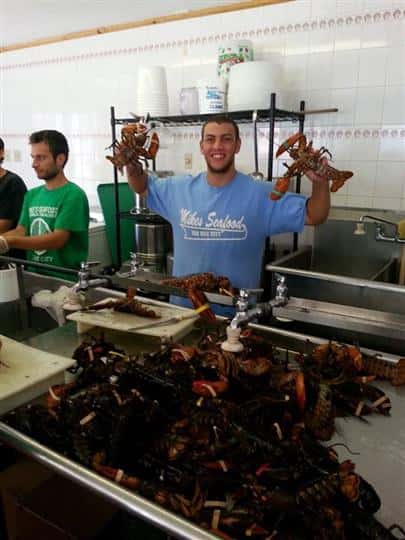 workers holding up the cooked lobsters in the kitchen