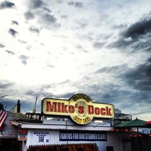 a view of mike's dock seafood raw bar sign with a cloudy sky