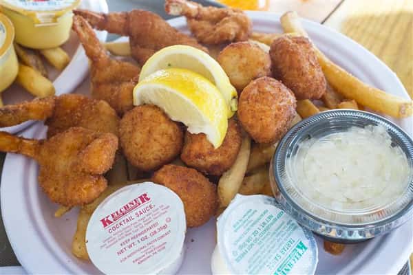 fried clams and hushpuppies with a side of fries, tartar sauce and lemon wedges