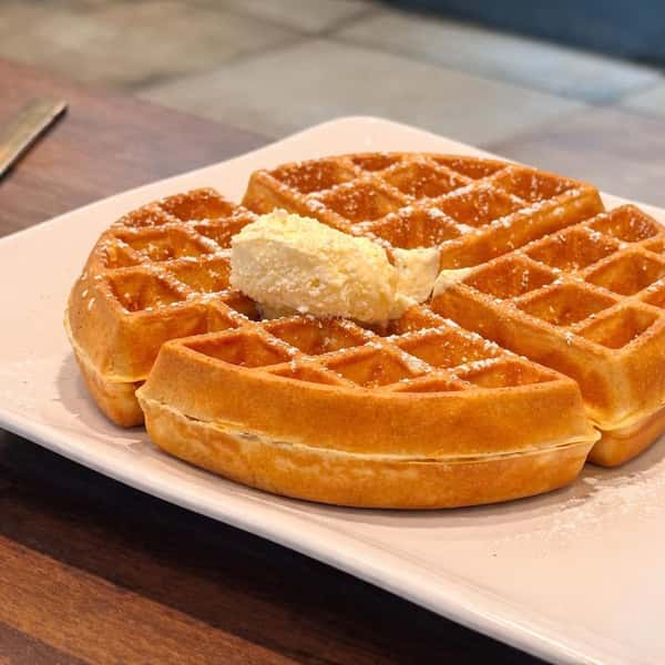 Belgian waffle topped with butter on a white plate