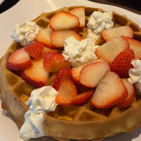 Belgian waffle topped with strawberries and whipped cream