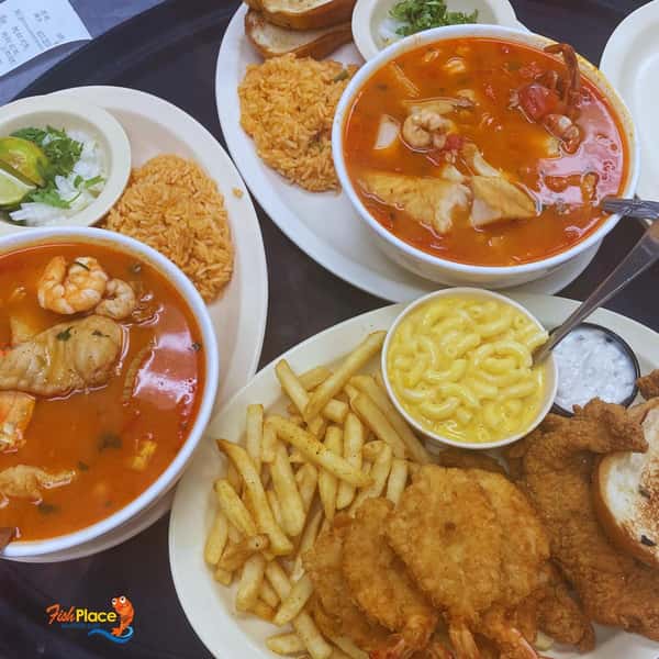 Two bowls of seafood soup served with french fries and fried fish