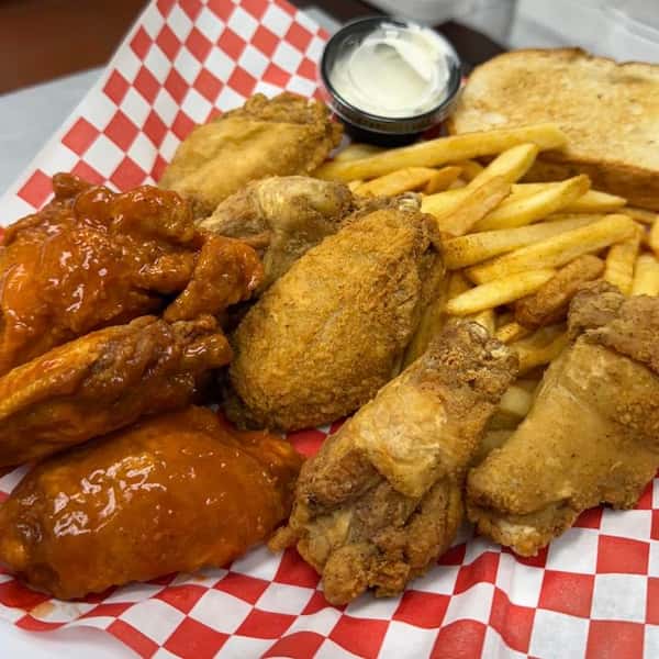 Basket of fried chicken wings with french fries and dipping sauce