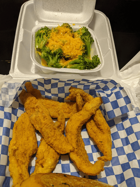 Fried fish tenders with a to-go container of salad