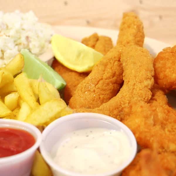 Close-up of fried shrimp and fries with lime and dipping sauces