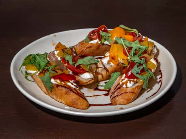 Toasted crostini topped with whipped ricotta, cherry tomatoes, arugula, and a drizzle of balsamic glaze.