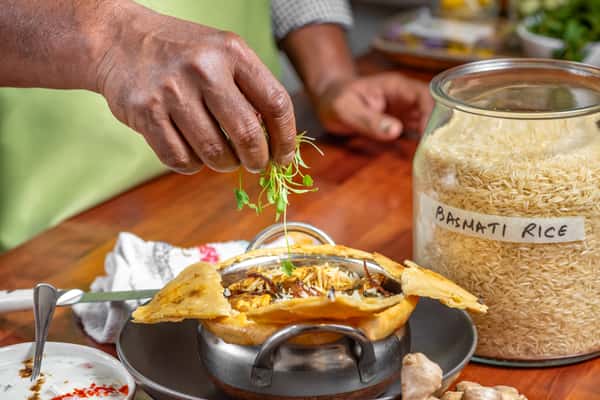 Chef Prasad's hands garnishing chicken biryani