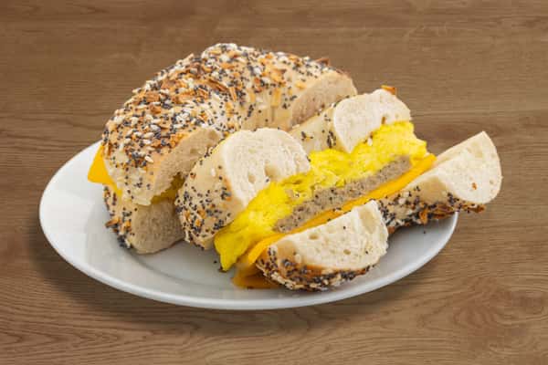 Close-up of a breakfast bagel sandwich with sausage, egg, and melted cheddar cheese.
