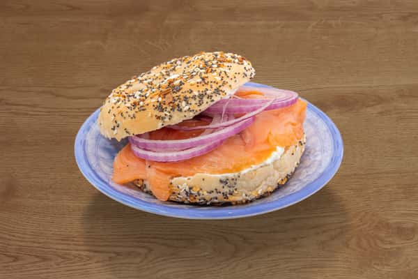 Smoked salmon and cream cheese bagel with red onion served on a blue plate.