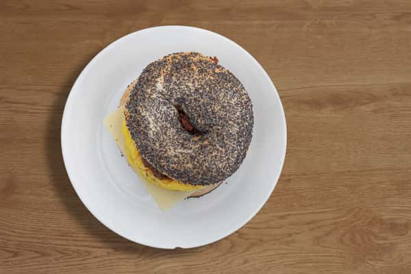 Top-down view of a breakfast sandwich on a seeded bagel with melted cheese.