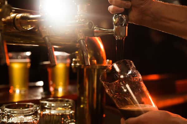 Bartender pours a dark beer at City Limits Bar and Grill, featuring brass taps and amber lighting.