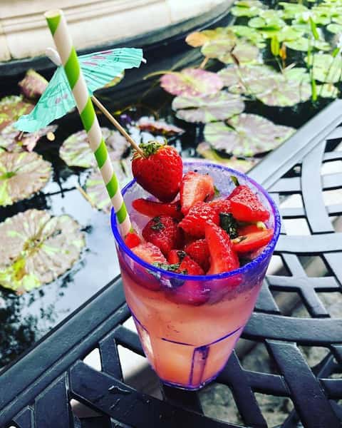 mixed cocktail in a glass with a straw and fresh strawberries