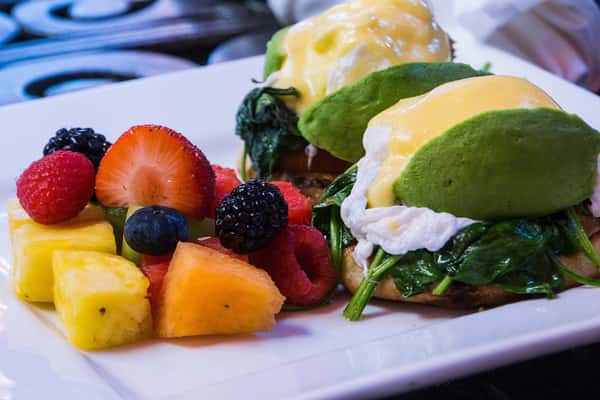 eggs benedict sandwich with a side of fresh fruit