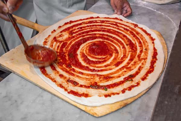 Spreading sauce on a pizza