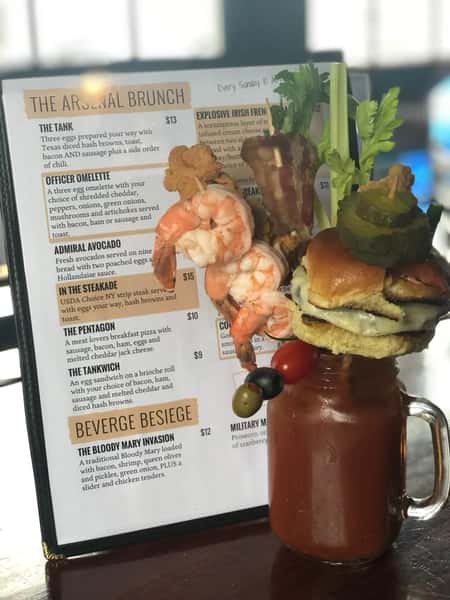 A bloody Mary topped with shrimp, bacon, celery, and a mini cheeseburger sider on a stick
