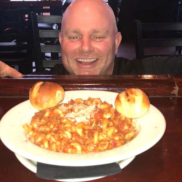 Dan smiling behind a plate of pasta Bolognese