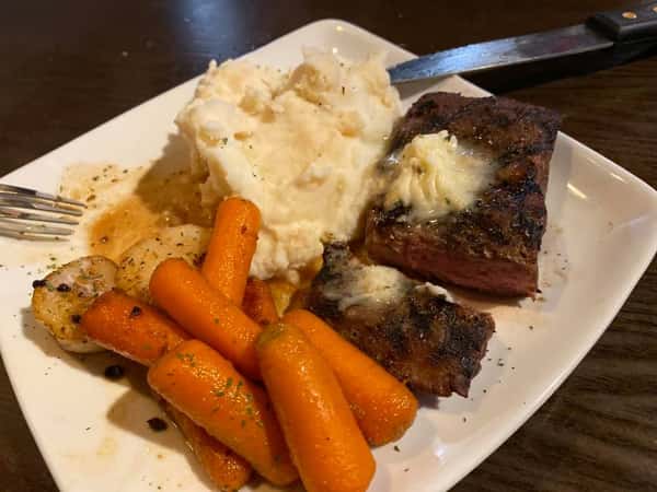 Steak with a side of cooked carrots and mashed potatoes