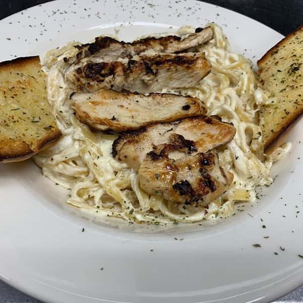 Spaghetti with alfresco sauce, topped with grilled chicken and a side of toasted garlic bread