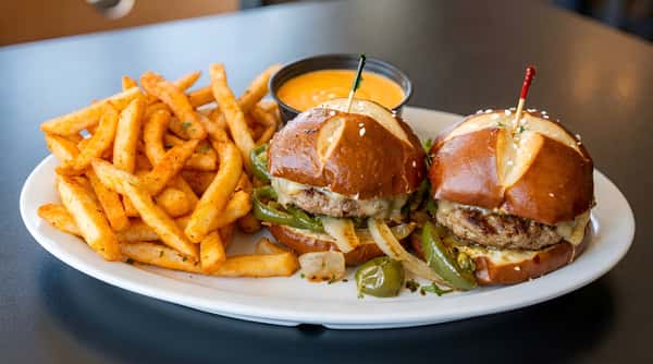 Sliders on pretzel buns with sauteed onions and peppers, served with seasoned fries and dipping sauce.