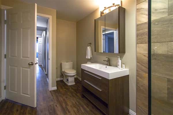 Bathroom with sink, mirror, toilet and open door leading to hallway