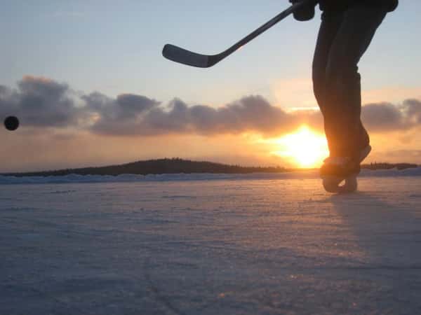 Low-angle shot of person playing hockey on ice in front of sunset