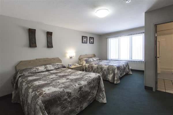 Room with two beds, night table, lamp, bathroom