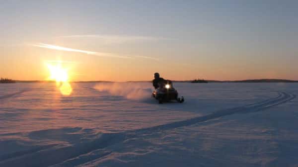 Snowmobiler on trail in front of sunset