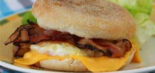 Egg, cheese, bacon on english muffin with lettuce on the side.