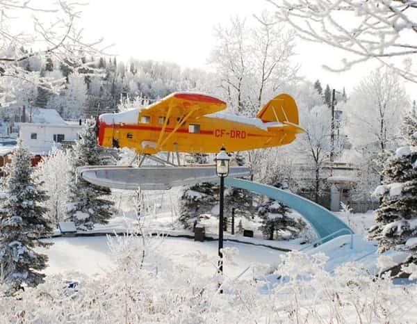 Elevated sea plane on display near snow-covered trees