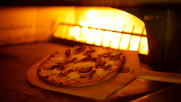 Pizza being freshly cooked in oven with flames