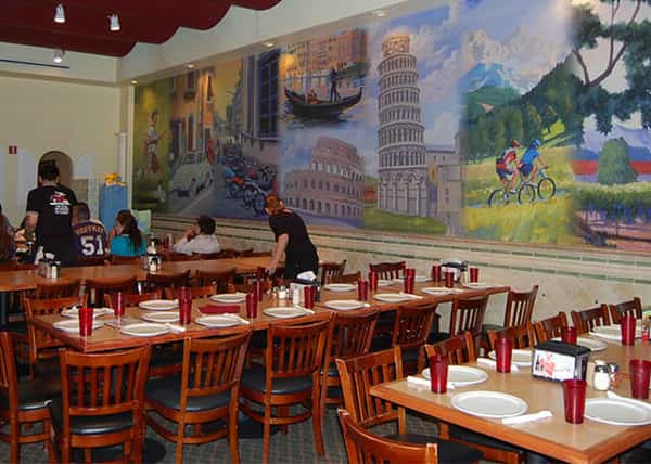 several tables set up for dinner with a mural