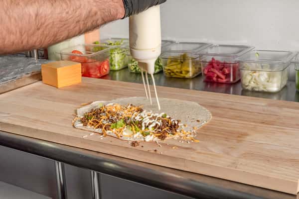 Chef squeezing sauce over a wrap